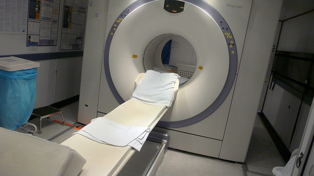 A PET-CT scanner and patient table in an empty imaging room.