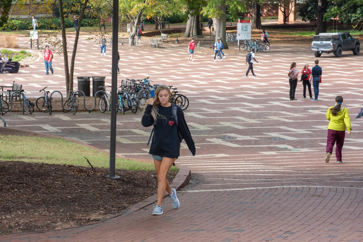 Students walking across a tree-lined university courtyard.